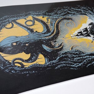 K&ouml;nnte beinhalten: Eine Schwarzwei&szlig;illustration eines riesigen Kraken mit leuchtenden Augen, der aus einem wirbelnden, dunkelblauen Meer zu einem Schiff mit wei&szlig;en Segeln greift. Der Krake ist von einem gelben und wei&szlig;en Sternenhimmel umgeben.
