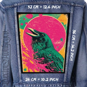 Puede incluir: Chaqueta vaquera con un parche rectangular grande con un cuervo verde sobre un fondo rosa y amarillo. El parche mide 32 cm por 36 cm, y 26 cm. El cuervo tiene el pico abierto.