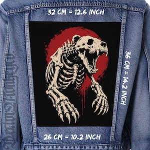 Peut inclure: Une veste en jean bleu avec un grand écusson rectangulaire au dos représentant un squelette d'ours sur fond circulaire rouge. L'écusson mesure 32 cm sur 36 cm, soit 12,6 pouces sur 14,2 pouces, avec une largeur inférieure de 26 cm ou 10,2 pouces.