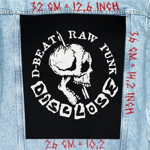 May include: A black patch with a white skull graphic and the words "D-BEAT RAW PUNK DISCLOSE" in a circular design. The patch is on a light blue denim jacket. The patch measures 12.6 inches wide and 14.2 inches high.