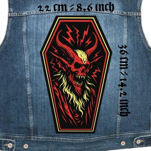 May include: A denim vest with a large, coffin-shaped patch featuring a red demon skull with yellow horns and lightning bolts. The patch measures approximately 8.6 inches by 14.2 inches.