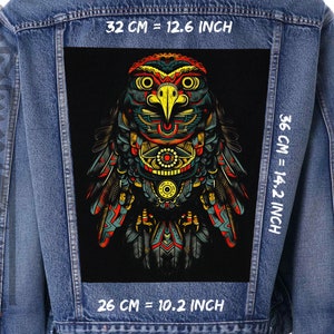 Op de afbeelding: Een spijkerjack met een zwarte patch met een kleurrijk, geometrisch uilontwerp. De patch is 26 cm breed en 36 cm hoog. Het jack heeft witte tekst op de voor- en achterkant, die de afmetingen in inches en centimeters aangeeft.