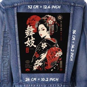 May include: A blue denim jacket featuring a large rectangular back patch with a graphic of a Maiko in a black kimono, red sun, and cherry blossoms. The patch measures 12.6 inches by 14.2 inches, with text including Maiko, Kyoto, and Rooted in Tradition.