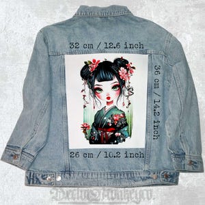 May include: An iron-on patch featuring a cartoon illustration of a girl with black hair, green eyes, and pink flowers in her hair. She is wearing a green and black kimono with red accents. The patch measures 36 cm by 26 cm.