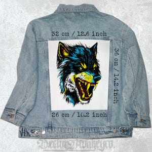 May include: A blue denim jacket with a white patch featuring a colorful illustration of a snarling wolf's head. The patch is 14.2 inches tall and 10.2 inches wide. The text "32 cm / 12.6 inch", "36 cm / 14.2 inch", and "26 cm / 10.2 inch" is printed on the jacket.