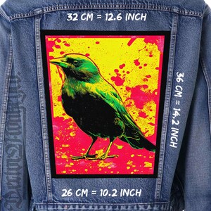 May include: A denim jacket with a large, rectangular patch featuring a green and black bird illustration against a yellow and red background. The patch measures 12.6 inches by 14.2 inches and 10.2 inches.