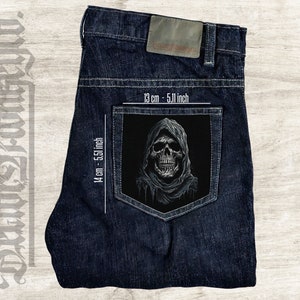 May include: A black and white skull with a hood patch on a pair of blue denim jeans. The patch measures 13 cm by 14 cm.