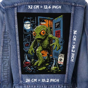 May include: A blue denim jacket featuring a large rectangular back patch with a graphic of a green creature in a laboratory. The patch measures 12.6 inches wide by 14.2 inches high, with a 10.2 inch base. The print includes text reading LAB 07 and CAUTION BIOHAZARD.