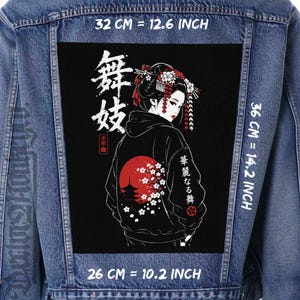 May include: A blue denim jacket featuring a large rectangular back patch with a graphic of a person in traditional attire, a red sun, cherry blossoms, and Japanese text. The patch measures 32 cm by 26 cm at the top and bottom, and 36 cm in height.
