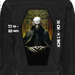 May include: Black denim jacket with a large, detailed iron-on patch of a vampire in a coffin. The patch measures 22 inches by 14.2 inches.