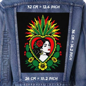 Puede incluir: Una chaqueta de mezclilla azul con un parche rectangular grande en la espalda. El parche muestra a una mujer con una rosa roja en el cabello dentro de un corazón, rodeada de cactus y flores. Dimensiones: 32 cm por 36 cm por 26 cm.