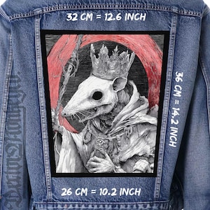 Peut inclure: Veste en jean avec un grand écusson rectangulaire représentant une illustration détaillée d'un rat couronné et vêtu d'une robe, sur fond de halo rouge. L'écusson mesure 32 cm sur 36 cm.