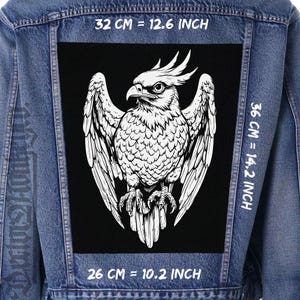 May include: A denim jacket with a large black patch showing a detailed white illustration of a bird of prey. The patch measures 32 cm wide, 36 cm tall, and 26 cm across the bottom.