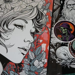 K&ouml;nnte beinhalten: Schwarz-Wei&szlig;-Illustration einer Frau mit Blumenschmuck und einem rot-grauen floralen Hintergrund. Zwei runde Aufkleber mit Totenkopfmotiven, einer mit einem Skelett mit lila Hut, sind ebenfalls zu sehen.