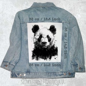 Pode incluir: Uma ilustração de aquarela em preto e branco de um rosto de panda em uma jaqueta de jeans. A ilustração tem 36 cm de altura e 26 cm de largura.