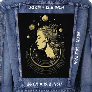 Könnte beinhalten: Eine schwarze Jeansjacke mit einem gold-schwarzen Patch, der ein Frauen Gesicht zeigt, umgeben von Sternen und Monden. Der Patch misst 36 cm x 26 cm, oder 14,2 Zoll x 10,2 Zoll.