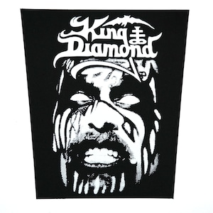 May include: Black and white patch featuring a stylized portrait of a man with white eyes and facial markings. The text "King Diamond" is above the portrait in a gothic font.