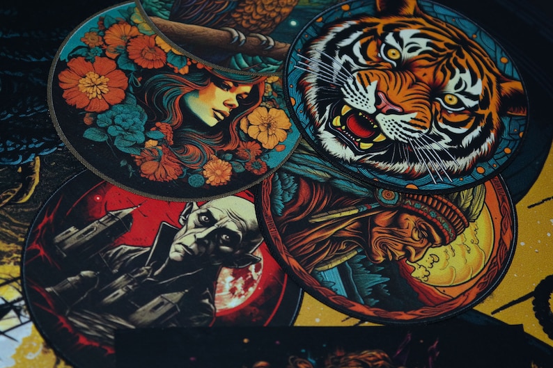 May include: Five round, colourful patches with various designs. The patches feature a woman with flowers, a tiger, a Native American, a vampire, and a cityscape.