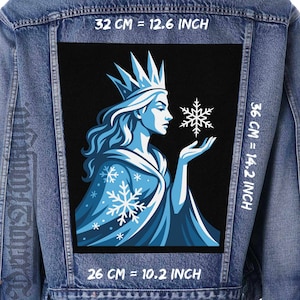 Peut inclure: Veste en jean avec un grand patch rectangulaire représentant une illustration bleu clair d'une femme couronnée tenant un flocon de neige. Le patch mesure 32 cm de large, 36 cm de haut et 26 cm de long.