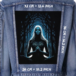 Könnte beinhalten: Eine blaue Jeansjacke mit einem schwarzen und blauen Grafik-Patch, das eine Frau mit langen weißen Haaren zeigt, die in einem Wald steht. Der Patch ist 32 cm breit, 36 cm hoch und 26 cm tief.