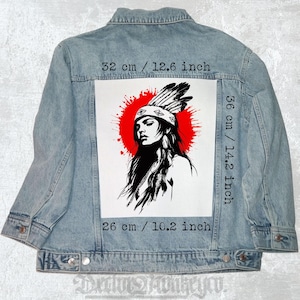 Puede incluir: Chaqueta vaquera azul claro con un gran gráfico en la espalda. El gráfico representa a una mujer nativa americana en blanco y negro, sobre un diseño de salpicaduras rojas. Mide 32 cm de ancho por 36 cm de alto.