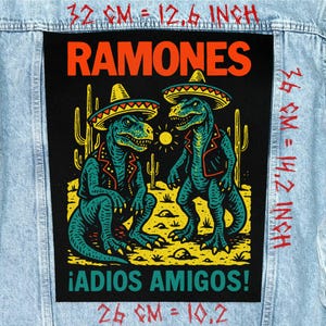 May include: A black patch featuring two cartoon dinosaurs wearing sombreros and jackets, with the word "RAMONES" in orange. The phrase "¡ADIOS AMIGOS!" is below the dinosaurs. The patch measures 12.6 inches by 14.2 inches.