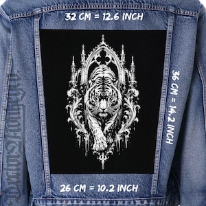 Può includere: Una giacca di jeans blu con una grande toppa rettangolare nera sul retro. La toppa mostra un'illustrazione di una tigre bianca incorniciata da archi gotici e ornamenti. Le dimensioni sono 32 cm di larghezza per 36 cm di altezza, base di 26 cm.