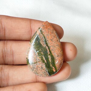 May include: A teardrop-shaped pendant made of red and green jasper with a polished finish.