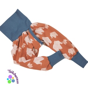 May include: Orange and blue children's pants with a white elephant print. The pants have a wide waistband and cuffed legs.