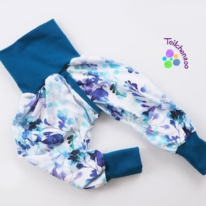 Puede incluir: Pantalones de bebé de color azul y blanco con estampado floral, puños y cintura de color azul turquesa. Los pantalones tienen un aspecto fruncido alrededor de la cintura y las piernas.