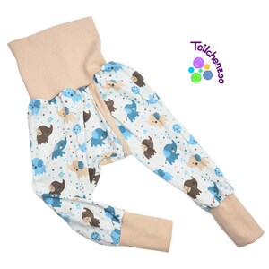 May include: Blue and brown elephant print baby pants with a beige waistband and cuffs. The pants have a zipper closure and are made of soft, comfortable fabric.