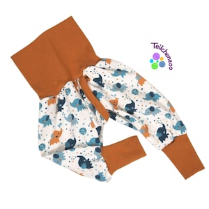 May include: Orange and white baby pants with a pattern of blue elephants and stars. The pants have a wide elastic waistband and cuffed legs.