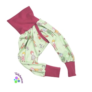 May include: A green and burgundy children's jumpsuit with a playful print of people and animals. The jumpsuit has a turtleneck and long sleeves with burgundy cuffs.