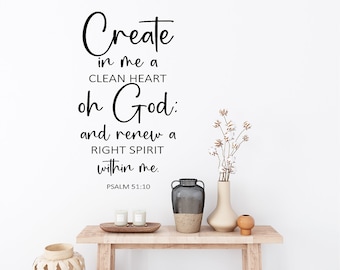 Pode incluir: Uma mesa de console de madeira com itens decorativos contra uma parede branca. A parede apresenta o texto "Cria em mim um coração puro, ó Deus, e renova em mim um espírito reto. Salmo 51:10." Vasos decorativos e velas estão na mesa.