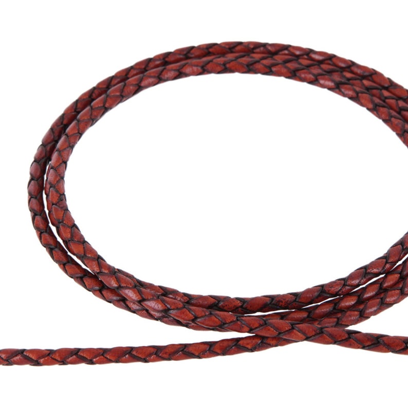 May include: A close-up of a brown leather cord, braided in a flat, woven pattern.
