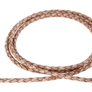 May include: A close-up of a light brown braided leather cord. The cord is woven in a diamond pattern and is coiled into a circle.