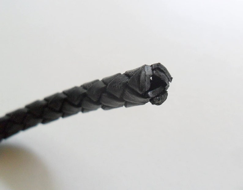 May include: Close-up of a black braided leather cord.