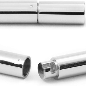 May include: Two silver metal tube-shaped clasps for jewelry making. The clasps are open and ready to be attached to a necklace or bracelet.