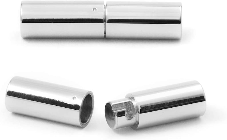 May include: Two silver metal tube-shaped clasps for jewelry making. The clasps are open and ready to be attached to a necklace or bracelet.