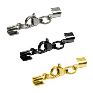 Könnte beinhalten: Drei silberne, schwarze und goldene Karabinerverschlüsse mit einem kleinen Ring und einem quadratischen Endstück. Diese Verschlüsse werden für die Schmuckherstellung verwendet.
