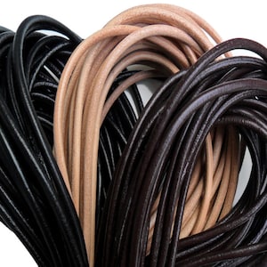 Può includere: Primo piano di tre bobine di cordoncino in pelle. I cordoncini sono neri, marroni e beige naturale. I cordoncini hanno tutti lo stesso spessore e sono avvolti strettamente insieme.