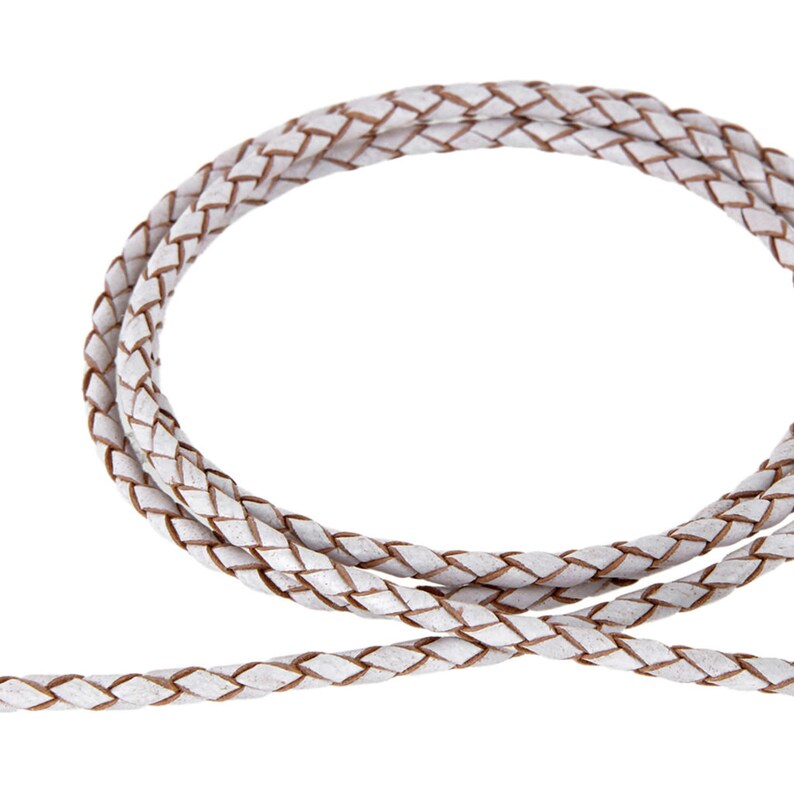May include: White braided leather cord with a brown undertone. The cord is woven in a simple braid pattern.