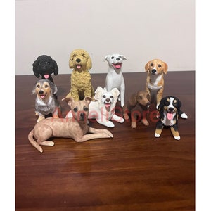 May include: A collection of eight dog figurines, each depicting a different breed and pose. The figurines are made from painted ceramic and feature realistic details. The dogs are arranged in a group on a wooden surface.