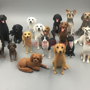 May include: A collection of fifteen small animal figurines featuring various dog breeds and one cat. The figures are rendered in diverse colors including black, white, brown, tan, and grey, with some displaying multi-colored coats and open mouths.