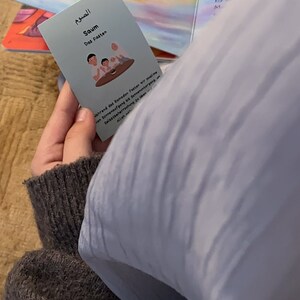 May include: A blue card with Arabic text and the word "Saum" which means "Fasting" in English. The card also has an illustration of three people sitting at a table. The text on the card reads: "During Ramadan, Muslims fast from sunrise to sunset. Self-discipline in obedience to Allah."