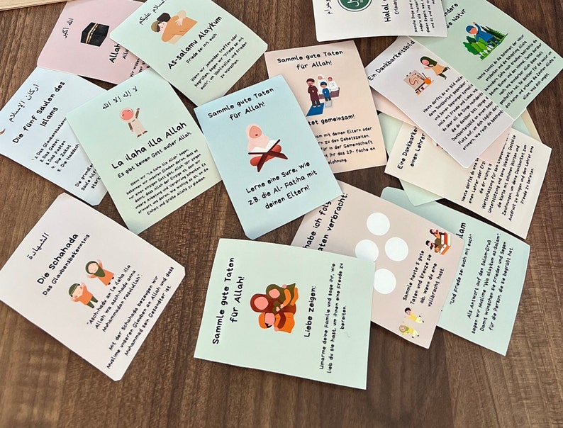 May include: A set of colorful cards with Islamic teachings and illustrations. The cards feature phrases in Arabic and German, such as "La ilaha illa Allah" and "Sammle gute Taten f&uuml;r Allah!" The cards are designed for children and feature illustrations of people praying, giving charity, and learning the Quran.