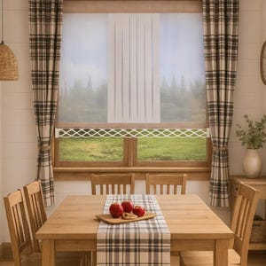 Può includere: Un tavolo da pranzo in legno con quattro sedie abbinate, caratterizzato da un runner a quadri con sopra un tagliere in legno con tre mele rosse. La finestra è decorata con tende a quadri e una tenda a rullo bianca con bordo a traliccio.