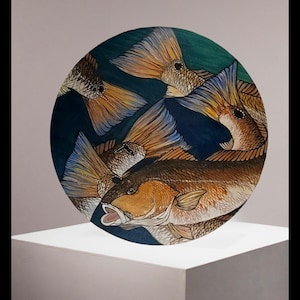 丸い木の壁画に描かれたレッドフィッシュと尾