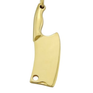 Könnte beinhalten: Eine goldfarbene Halskette mit einem Anhänger in Form eines Metzgermessers.