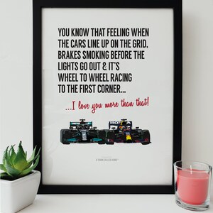 May include: A black and white print with a quote about the feeling of cars lining up on the grid before a race. The quote reads "You know that feeling when the cars line up on the grid. Brakes smoking before the lights go out & it's wheel to wheel racing to the first corner... I love you more than that!"  The print features a cartoon illustration of two race cars, one green and one red, side by side.